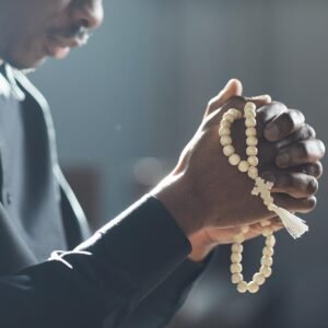 Close-up of African man holding beads in his hands and praying in the church